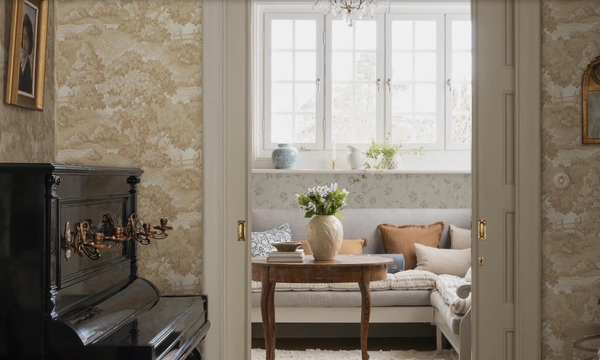 Обои Boråstapeter Alnarp Beige 8716 — пейзажный узор с деревьями в бежево-кремовых тонах в интерьере гостиной, чёрное пианино с канделябрами и анфилада с диваном, Boråstapeter Herrgård