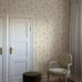 Интерьер коридора с флизелиновыми обоями Boråstapeter Luktärt Beige (арт. 8707). Узор с душистым горошком, фиалками, стрекозами и бабочками в мягких пастельных оттенках розового, зелёного и медово-жёлтого на кремово-белом фоне. Элегантная усадебная обстановка с белыми дверями, креслом в полоску, зелёным пуфом и шторами. Коллекция Herrgård от Boråstapeter.
