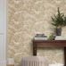 Интерьер прихожей с флизелиновыми обоями Boråstapeter Alnarp Beige (арт. 8716). Пышный пейзажный узор с деревьями, рекой и мостом в тёплой бежевой палитре. Уютная усадебная обстановка с консольным столиком, полосатым пуфом, книгами и растением. Коллекция Herrgård от Boråstapeter.