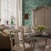 Интерьер гостиной с флизелиновыми обоями Boråstapeter Alnarp Blue&Green (арт. 8718). Пышный пейзажный узор с деревьями, рекой и мостом в насыщенной сине-зелёной палитре. Уютная усадебная обстановка с диванами, креслами, шкафом, столиком и свечами. Коллекция Herrgård от Boråstapeter.