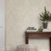 Интерьер гостиной с флизелиновыми обоями Boråstapeter Hildasholm Beige (арт. 8722). Крупноцветковый узор с пионами, васильками, ландышами и другими местными растениями в белых тонах на светло-бежевом фоне. Уютная усадебная обстановка с консольным столиком, книгами, растением и полосатым пуфом. Коллекция Herrgård от Boråstapeter.