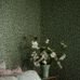 Фрагмент интерьера спальни декорированной обоями Hazel из каталога Falsterbo ll от Borastapeter с лиственным узором ветвей лесного ореха темно зеленого оттенка.