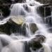 Фотопанно Fantasy waterfall с таинственным изображением сияющих потоков воды, низвергающихся по огромным зеленоватым валунам. Купить фотообои для стен в интернет-магазине, бесплатная доставка.