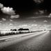 Фотообои Dream road, Mr. Perswall с черно-белым изображением шоссе, уходящего вдаль на фоне природы и высокого неба. Купить фотообои для гостиной, коридора в салонах ОДизайн, бесплатная доставка.