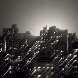Фотообои арт. DM309-1 Mr. Perswall с изображением контура ночного города в черно-белых тонах освещаемого лучами света из окон урбанистических домов. Купить фотообои  Mr. Perswall в Москве, большой ассортимент, оплата онлайн, бесплатная доставка